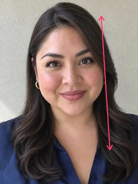 The same woman with long layers and a deep side part, a long arrow from the top of her head down past her shoulders