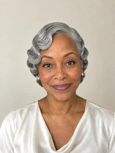 A Black woman in her sixties with short silver finger waves and a side part