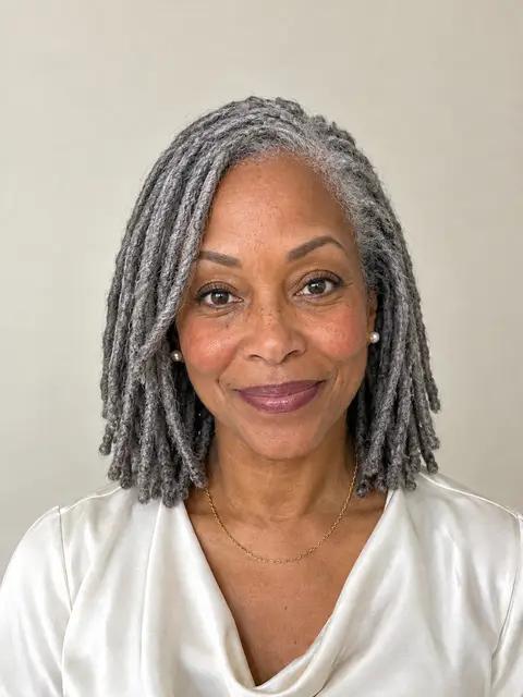 A Black woman in her sixties with shoulder-length silver locs
