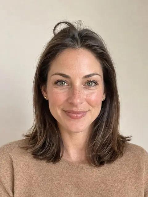 A woman with a cowlick at the front hairline, a tuft standing up beside her part