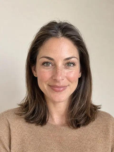 A woman with a smooth middle part and shoulder-length hair lying flat at the front